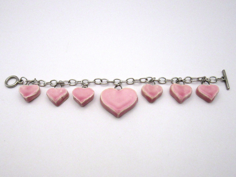 A Pink Handcrafted Ceramic Heart Dangle Charm Bracelet. Laid out flat. A pink handcrafted ceramic heart dangle charm bracelet.