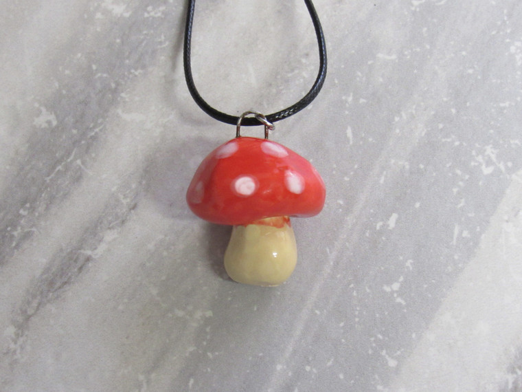 A ceramic red top Mushroom handcrafted necklace handmade jewelry. On a black corded necklace. A ceramic red top mushroom handcrafted necklace handmade jewelry . On a black cord necklace.