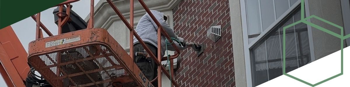 on cherry picker cleaning dryer vent on upper floor of complex