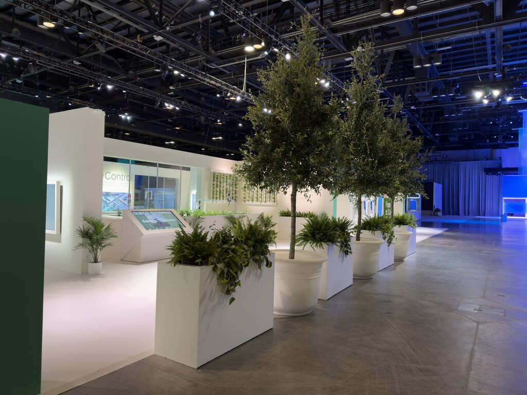 an exhibit lined with large potted trees and plants,