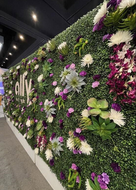 a wall of green hedges with fresh colorful flowers spread out. The name ally is centered.