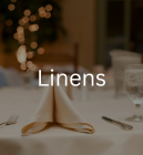 Linens written on a background of a table with a folded napkin, silverware, and a tablecloth