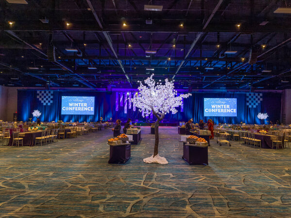 a indoor conference with various seating and 2 large monitors that read "Winter Conference"