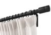 Black non-telescoping, steel, custom curtain rod set with Highland Forge's notched drum finial and a beige curtain.