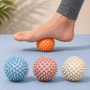 Spiky massage balls in white, orange, pink and blue used on foot — deep tissue trigger point relief for plantar fasciitis and muscle tension