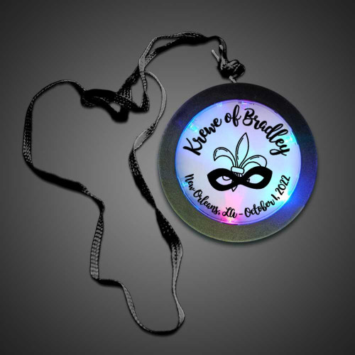 Flashing Medallions, illuminated medallion with customized event details and a decorative mask design.
