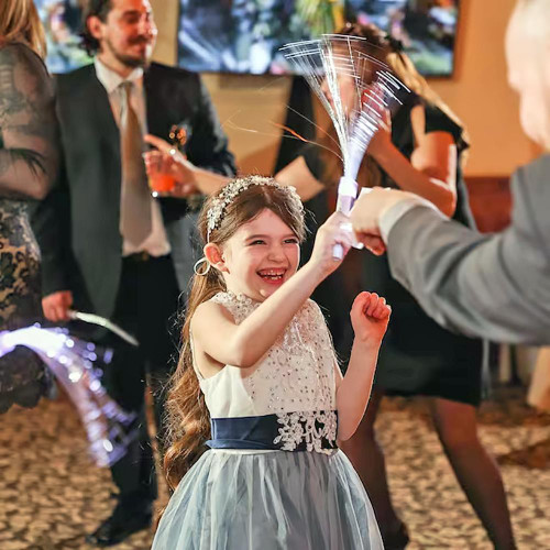 Fiber Optic LED Wands | Light Up Party Wands - Extreme Glow, a young girl holding a glowing fiber optic wand with bright streaks of light during a celebration or party.