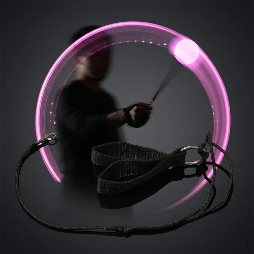illuminated purple LED poi ball spinning with a person in the background creating light trails in a dark environment