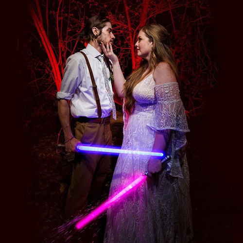 Customized Lightsaber Sword, two women holding glowing pink and blue lightsabers in a dark forest setting at night.