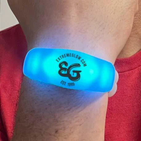 16 Mode Multicolor LED Bracelet, glowing blue LED wristband worn on a person's wrist with logo and website printed on it.