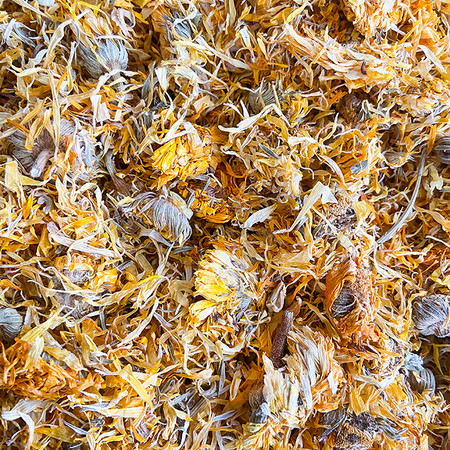 A close-up view of dried calendula whole flowers, featuring vibrant yellow and orange petals with green and brown accents from the flower heads. The dried flowers have a textured appearance, showcasing the delicate, fluffy petals and the structural details of the flower centers. The mix of colors and textures reflects the natural beauty of the dried calendula flowers. A close-up view of dried calendula whole flowers, featuring vibrant yellow and orange petals with green and brown accents from the flower heads. The dried flowers have a textured appearance, showcasing the delicate, fluffy petals and the structural details of the flower centers. The mix of colors and textures reflects the natural beauty of the dried calendula flowers.