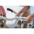 A caregiver adjusts the TelescoLift handle of an Invacare ISA XPLUS Stand-Up Electric Patient Lift beside a hospital bed, preparing for patient assistance.