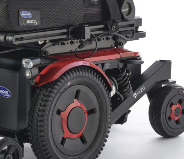 Close-up of the front wheel drive mechanism of an Invacare AVIVA FX motorized wheelchair, featuring sleek design and a red-black color scheme.