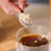 Scoop of Four sigmatic FOCUS powder being put into a mug of coffee. 