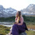 photo of a woman sitting in the enigma with a view of mountains in the back, the enigma in the picture is purple