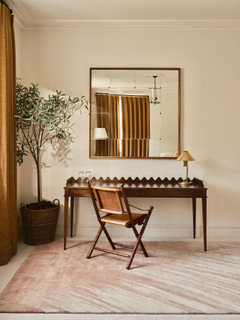 David Rockwell Splash Salmon rug beneath a scalloped oak desk and leather campaign chair, with an olive tree and antique mirror