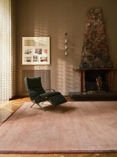 The Rug Company Margo rug, Peony colourway, styled in a living room beside a fireplace and reclining chair