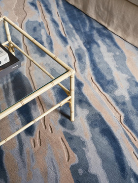 David Rockwell Fjord Frost rug, carved blue, sand and ivory pile beneath a faux-bamboo glass coffee table