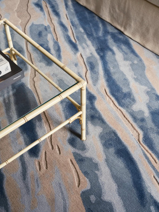 David Rockwell Fjord Frost rug, carved blue, sand and ivory pile beneath a faux-bamboo glass coffee table