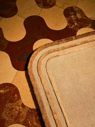 Arc rug in Amber, corner detail on a patterned marble floor