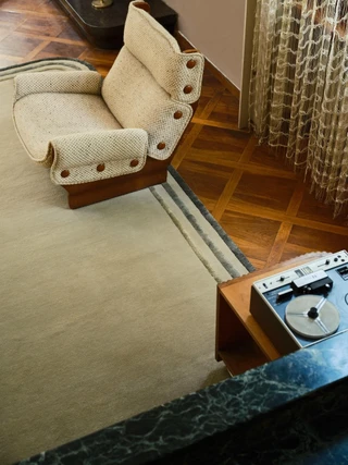 Arc rug in Spruce, styled vignette with an armchair and reel-to-reel cabinet