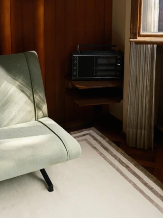 Portico rug in Birch, styled vignette with an upholstered lounge chair beside a window