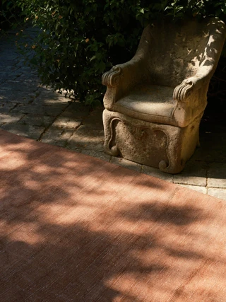 Vara rug in Clay, outdoor editorial detail beside a stone garden chair