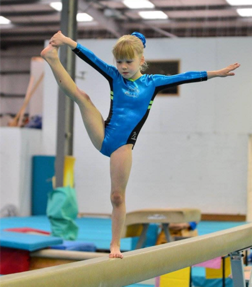 A young girl in a blue leotard balances on a beam at City of Preston Gymnastics Club, demonstrating flexibility and focus during training. A young girl in a blue leotard balances on a beam at City of Preston Gymnastics Club, demonstrating flexibility and focus during training.