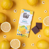 Lemon 45% Milk Chocolate bar next to unwrapped squares and lemons on yellow background