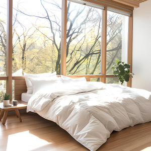 PrimaLoft TENCEL Cool Touch comforter on a bed with white sheets and a wooden floor nearby.