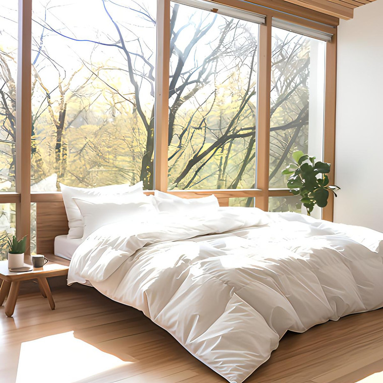 PrimaLoft TENCEL Cool Touch comforter on a bed with white sheets and a wooden floor nearby.