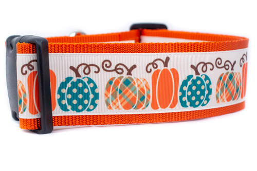 Orange dog collar with a white ribbon featuring a repeating pattern of orange, teal, and plaid pumpkins. 