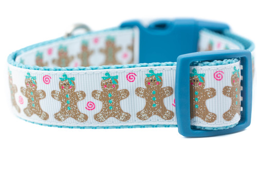 This 1 inch wide dog collar has glittery tan gingerbread men and with pink swirls and a blue bow on a white background. The 1 inch wide nylon is light blue and buckle style has blue buckle and slide.