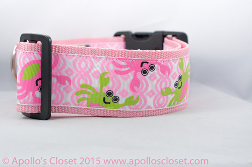 Pink dog collar with a repeating pattern of crabs in pink and green on a white background. 