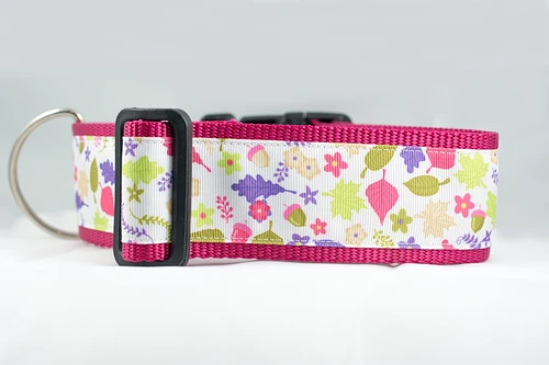 A pink dog collar with a white ribbon featuring a colorful floral and leaf pattern.