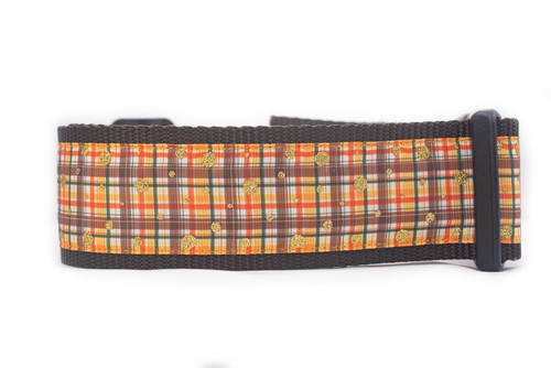 A brown dog collar with a plaid pattern in orange, brown, and white with gold glitter accents.