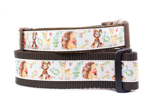 Brown dog collar with a white ribbon featuring woodland creatures like bears, deer, and hedgehogs. 