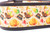 A brown dog collar with a pale orange background and a pattern of turkeys, pilgrim hats, pumpkins, corn and leaves.