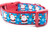 Waving Santa holding presents and a cookie on a blue background with stars and snowflakes.  Set on 1 inch wide red nylon webbing.