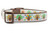 A close-up of a white dog collar with a colorful Thanksgiving theme. The collar features a repetitive pattern of small, funky turkeys with brown bodies and vibrant, sparkly tail feathers in orange, green, and blue swirl designs. The collar has brown edges, a brown plastic buckle, and a silver metal D-ring.