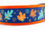 Multicolored fall leaves in brown, orange, lime and blue with swirls and dark blue background on an orange nylon.