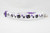 A white cat collar with a purple adjustable safety buckle and purple nylon. The collar has a repeating pattern of black cats with purple bows and purple paw prints.