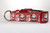 Red dog collar with a repeating pattern of Santa Claus and snowmen on a polka dot background.