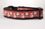 Red dog collar with a repeating pattern of Santa Claus and snowmen on a polka dot background.