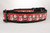 Red dog collar with a repeating pattern of Santa Claus and snowmen on a polka dot background.