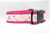 A pink dog collar with a white background and a floral pattern featuring leaves and flowers.