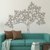 The sketched tree wall decal mural in brown vinyl color behind a couch in a living room.
