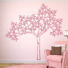 The sketched tree wall decal mural in lipstick vinyl color next to a chair on a light pink wall.