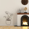 The hand drawn Swiss cheese potted plant wall decal next to a fireplace in brown vinyl.