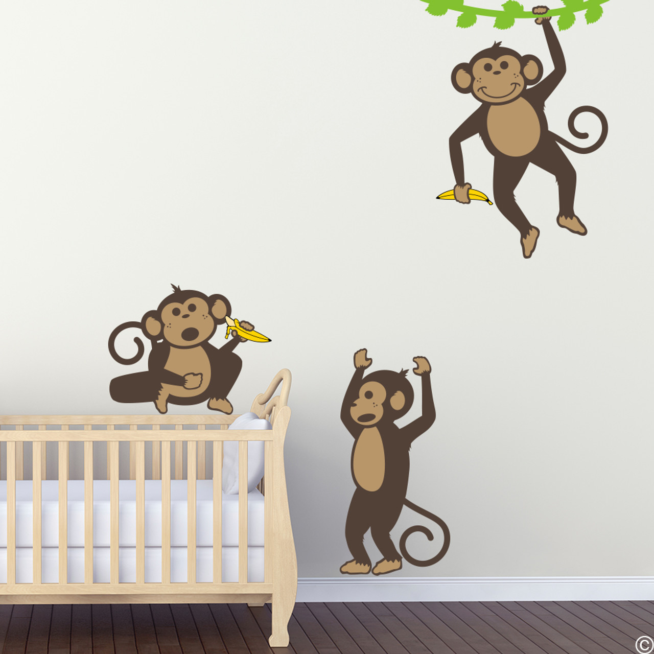 Vinyl wall decals of three monkeys holding bananas and playing .